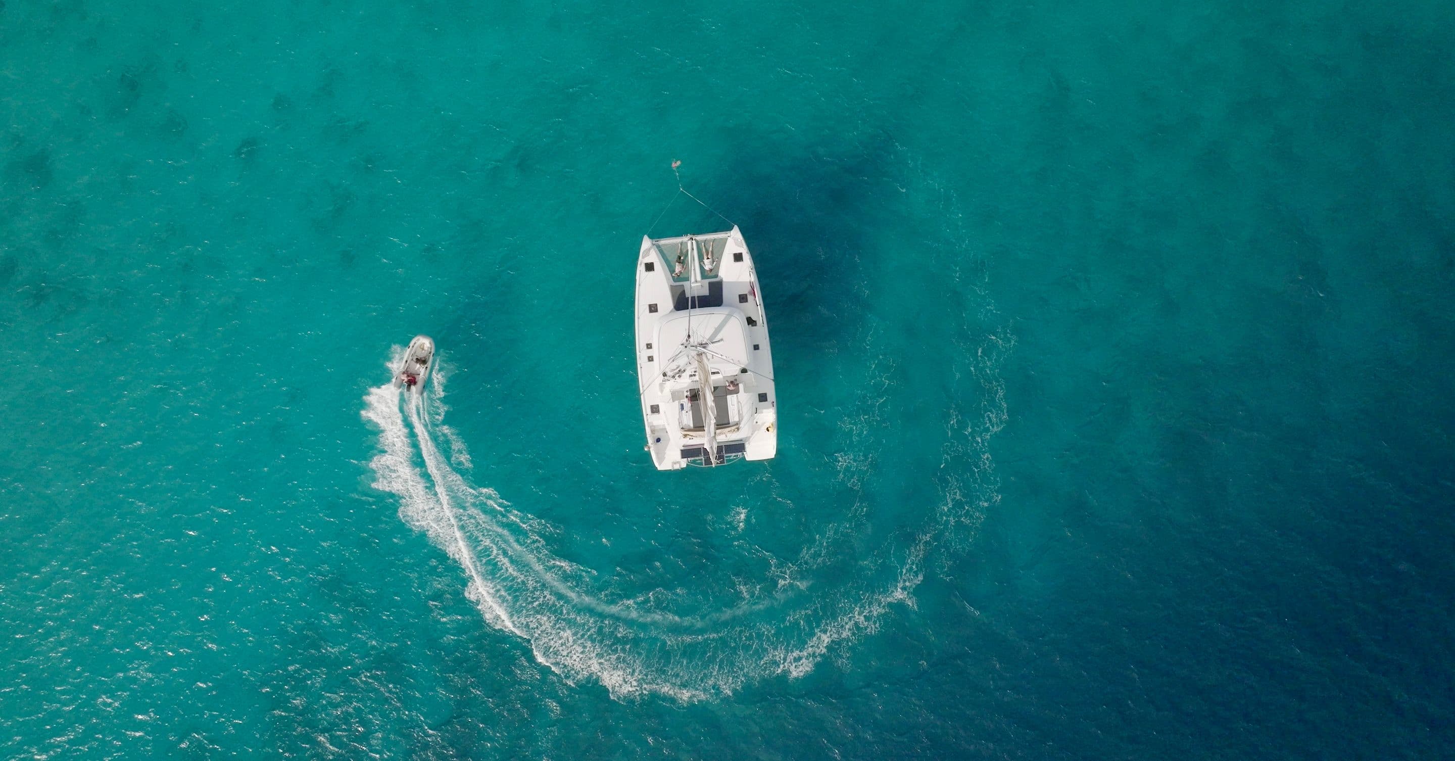 drone shot catamaran anchored dinghy moving round caribbean